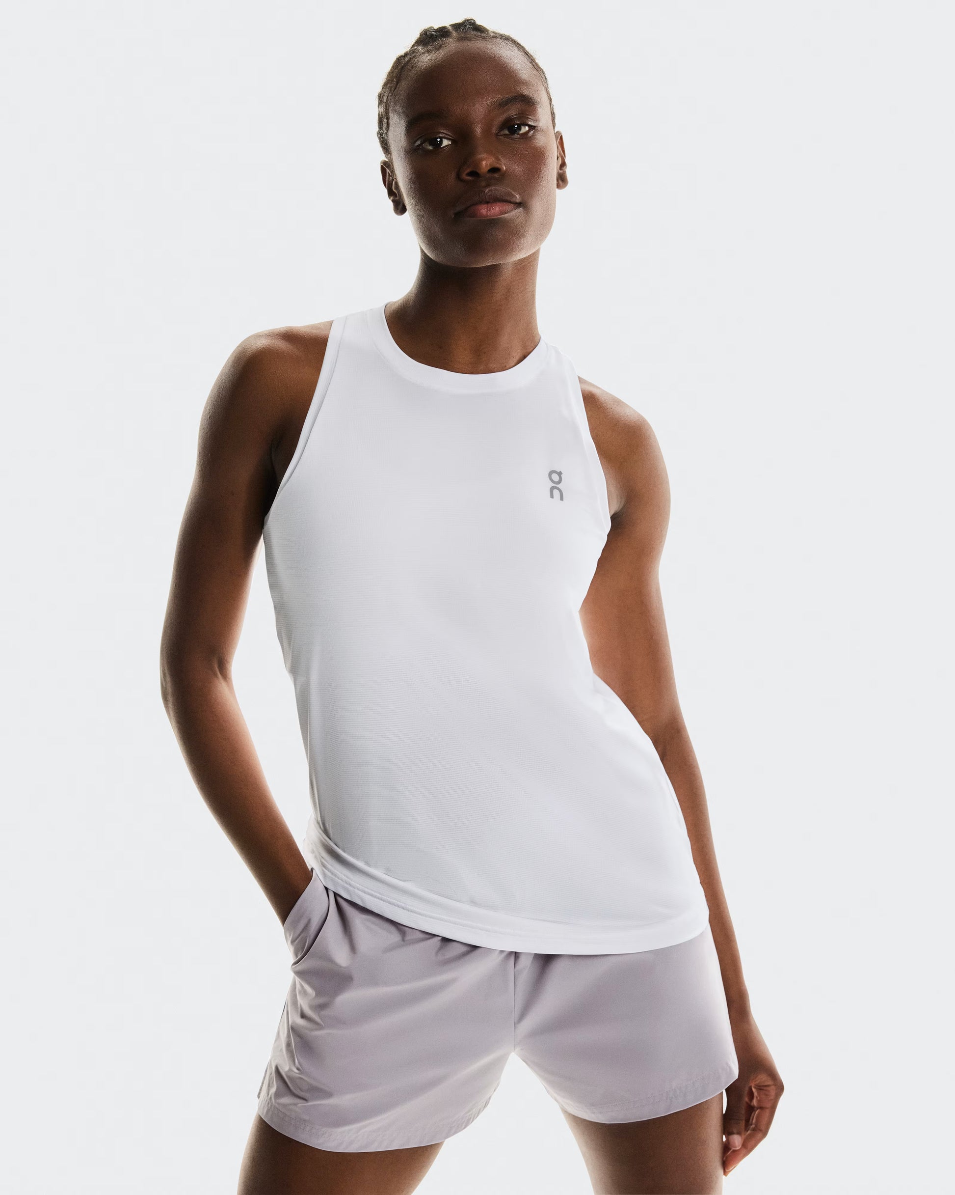 Woman wearing a white tank top and light gray shorts on a white background