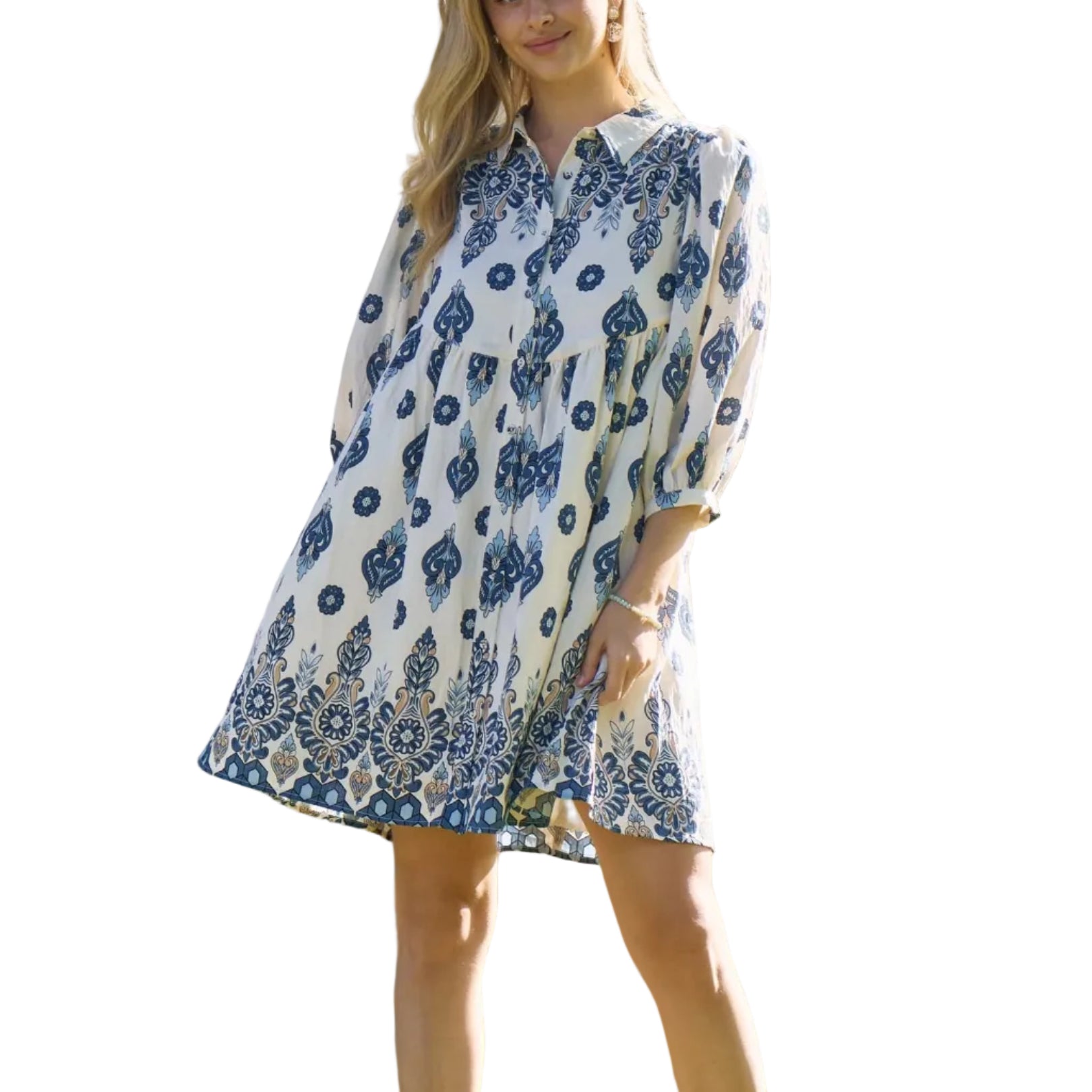 Woman wearing a blue and white patterned dress standing outdoors with trees in the background