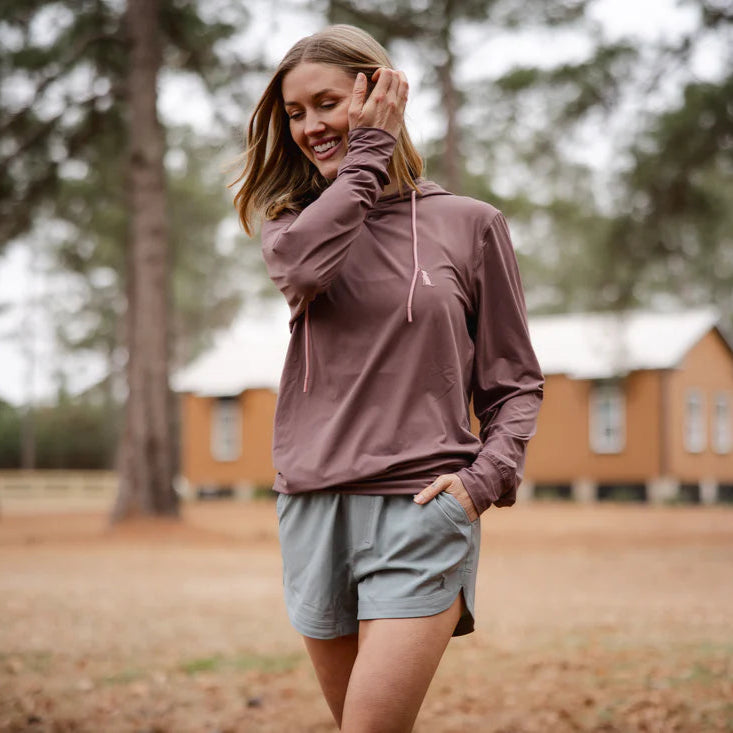 Woman in athletic wear standing in a park with wooden cabins in the background