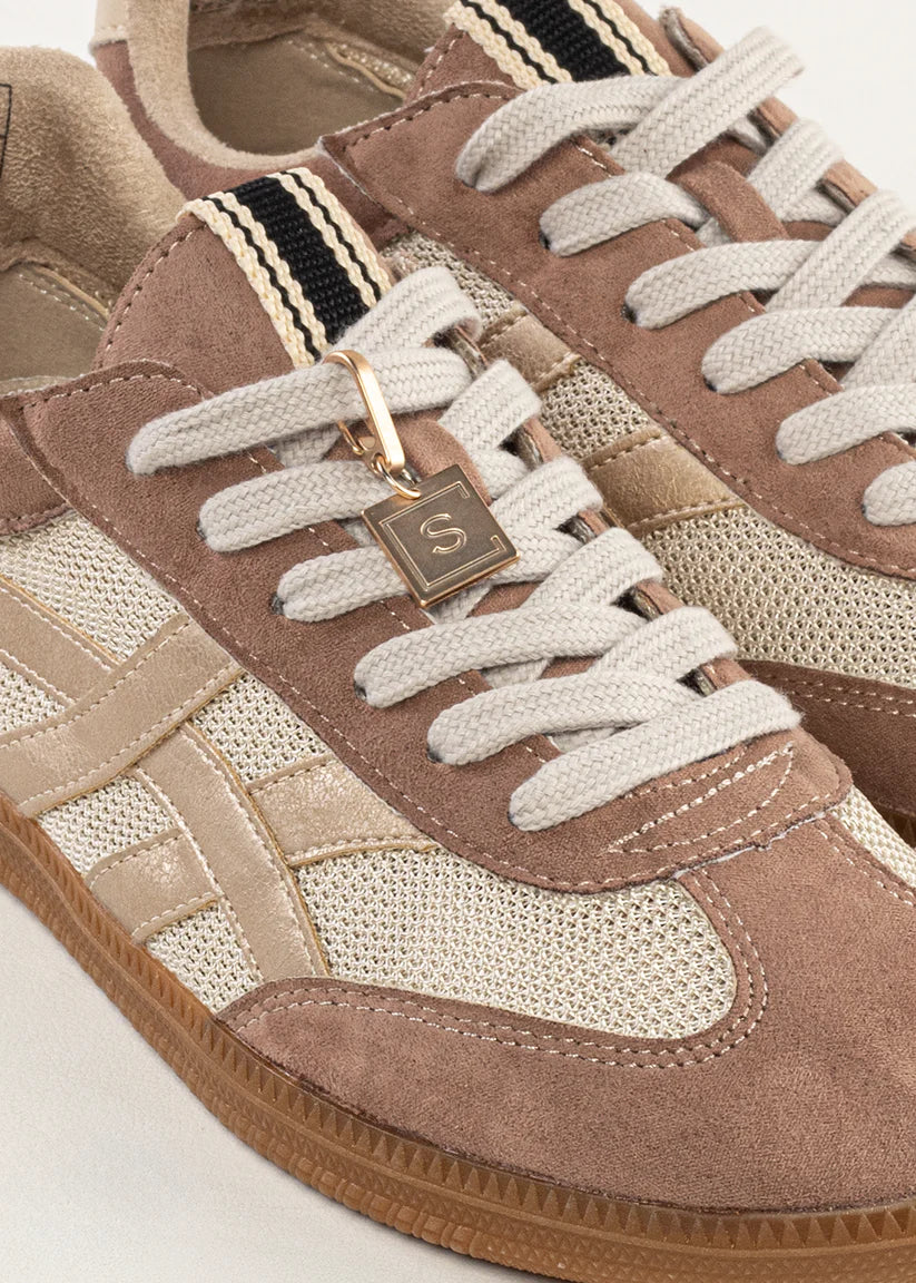 Close-up of a brown and beige sneaker with white laces on a light background