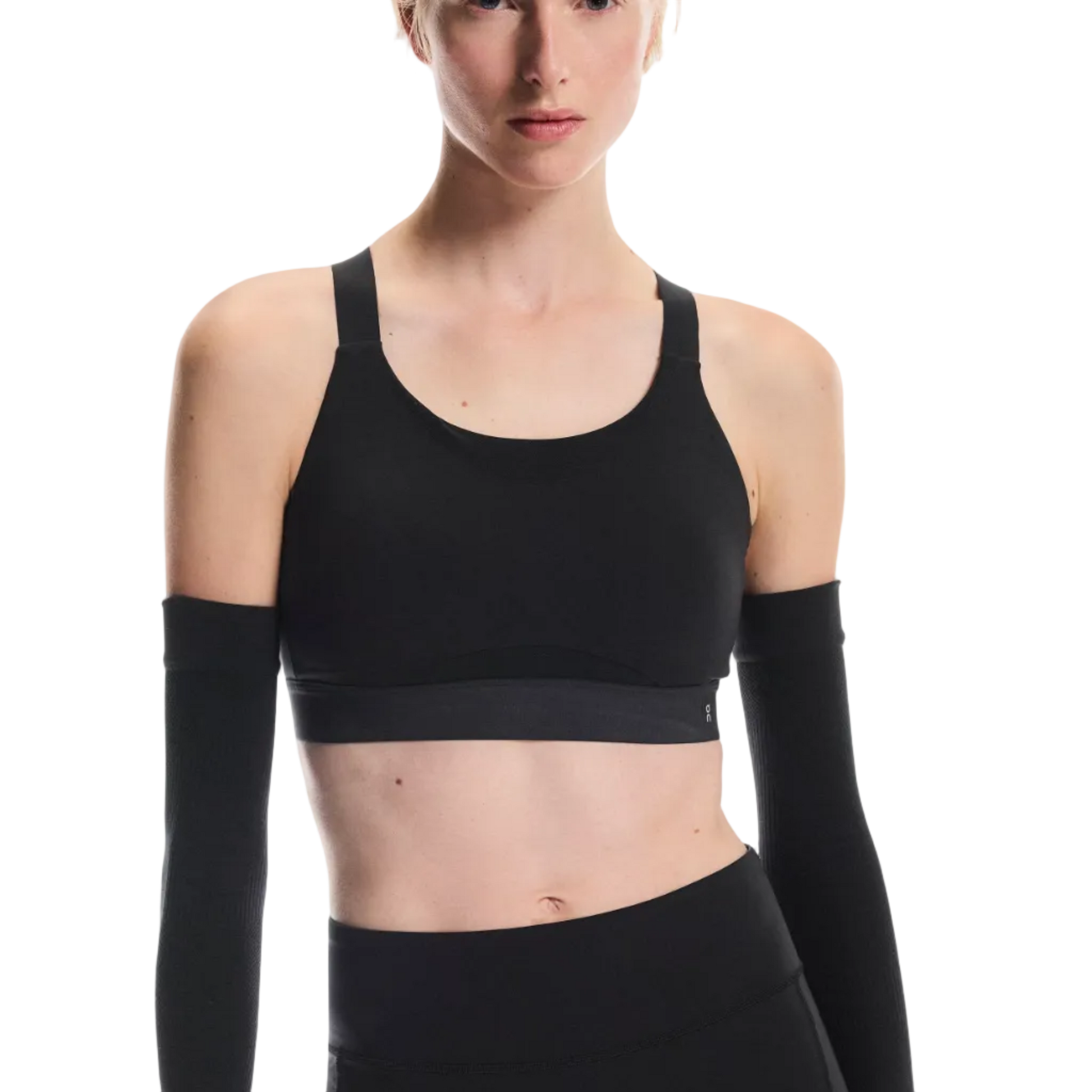 Person wearing a black sports bra and shorts with long-sleeve arm sleeves on a white background