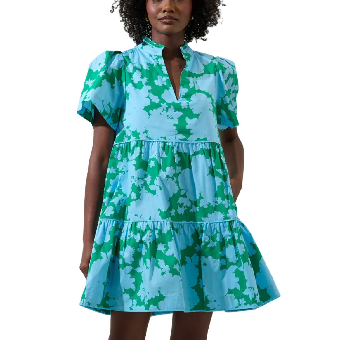 Woman wearing a green and blue patterned dress against a plain background