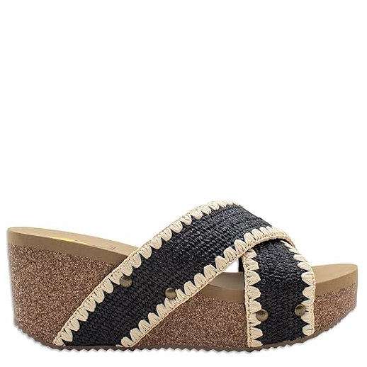 A woman's sandal with a cork wedge heel and black and beige crisscross straps.
