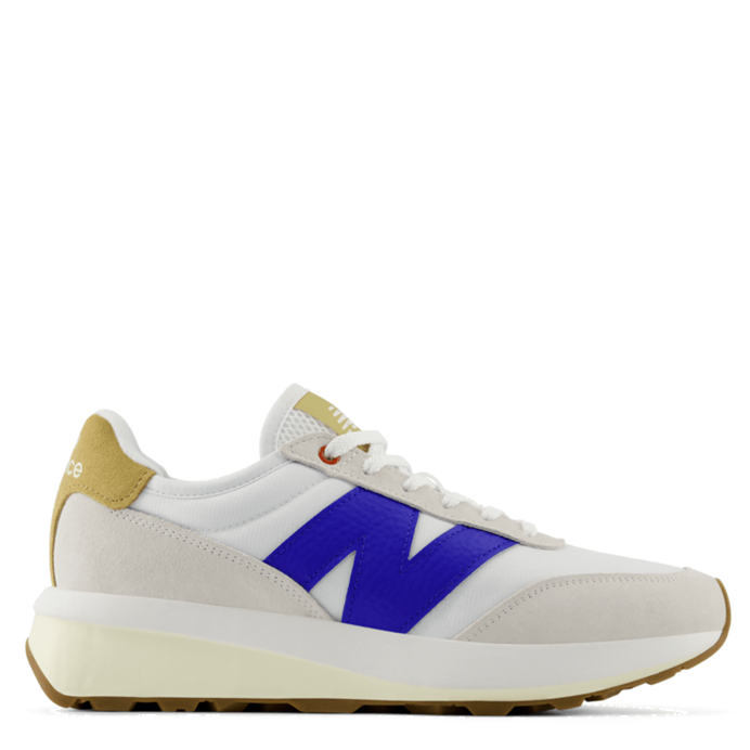 A New Balance sneaker in white, featuring a prominent royal blue 'N' logo on the side, a gold heel tab, and a cream-colored midsole and outsole.