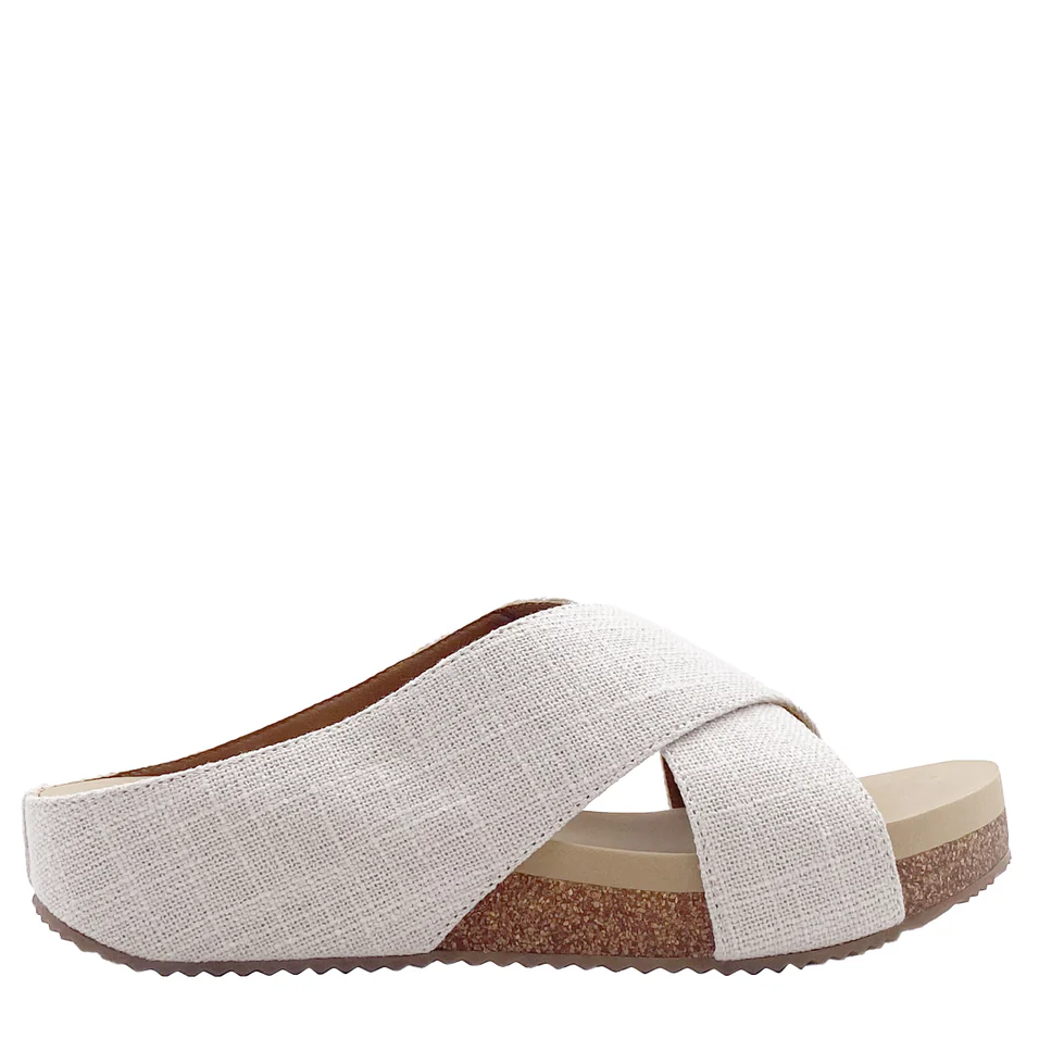 A white woman's sandal with a crisscross strap and a low wedge heel.