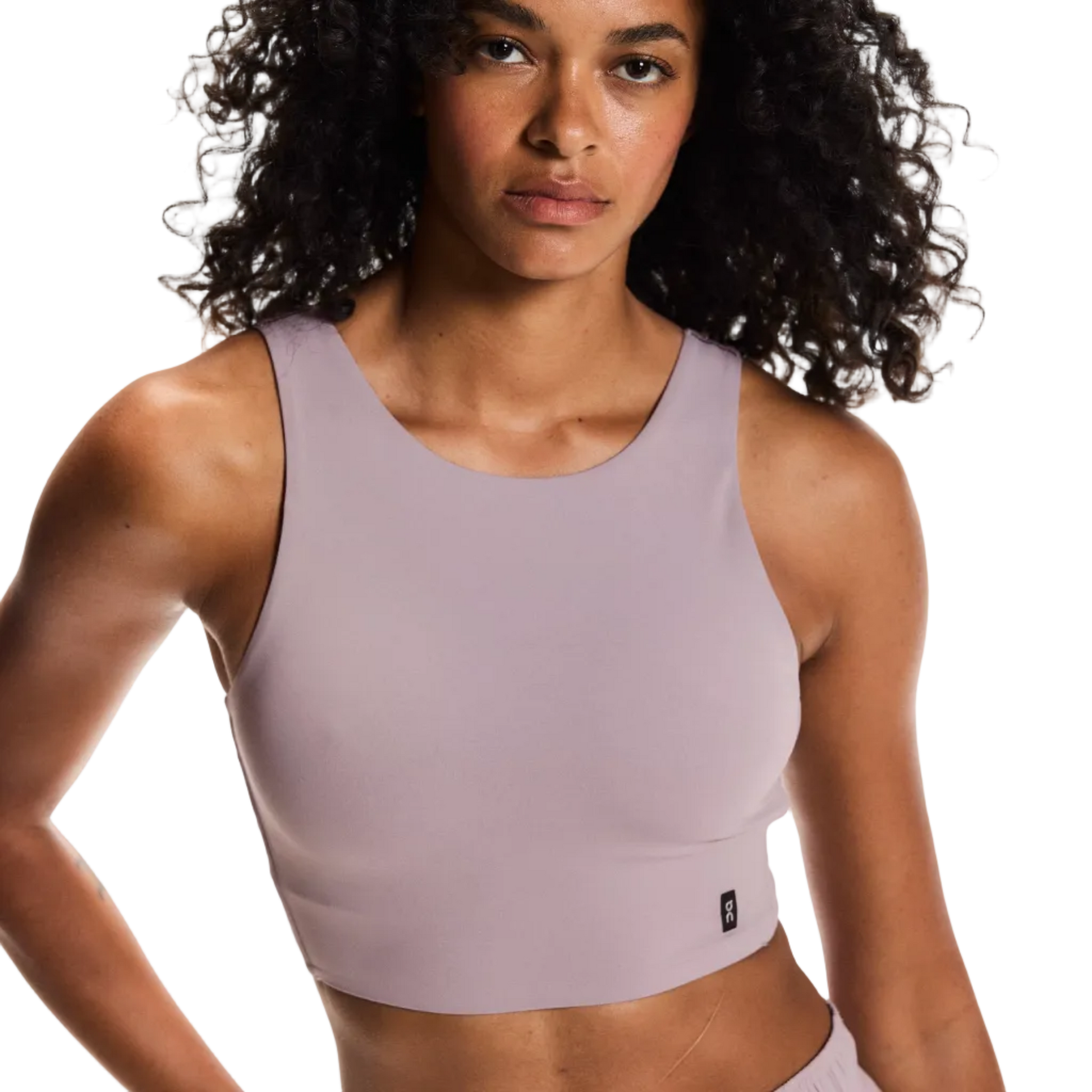 Woman wearing a light purple sports bra and shorts on a plain background