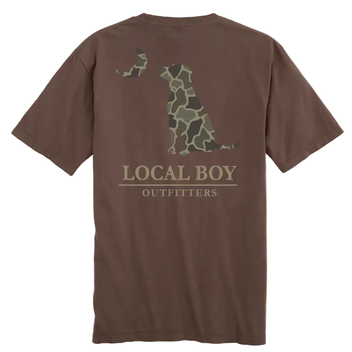 A brown short-sleeve t-shirt shown from the back, featuring a large graphic of a sitting dog in a green and brown camouflage pattern, with the text 'LOCAL BOY OUTFITTERS' printed below. A yellow circular 'NEW' badge is in the top-left corner.