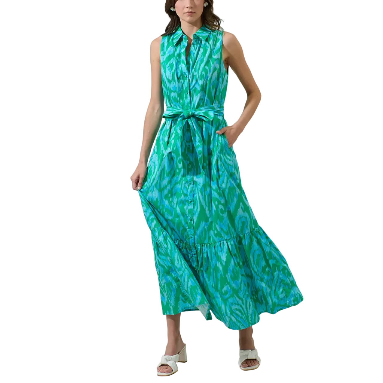 Woman wearing a green sleeveless dress with a pattern against a plain background