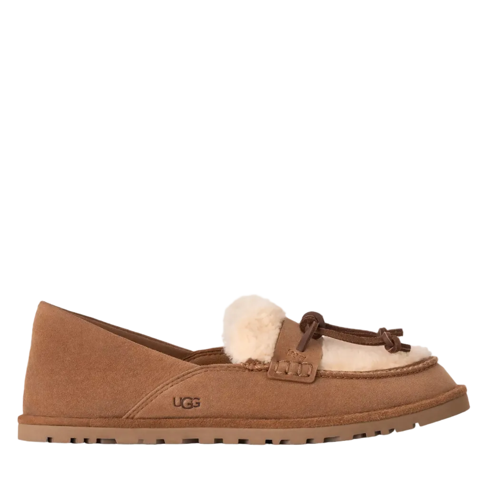 A single UGG slip-on loafer in tan suede with a fluffy cream shearling lining and a matching shearling pom-pom, shown in profile against a split white and light beige background.
