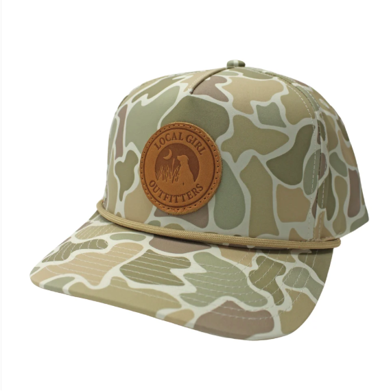 A rope hat with a muted sage green camo print, featuring the a round leather patch that says 'LOCAL GIRL OUTFITTERS' 