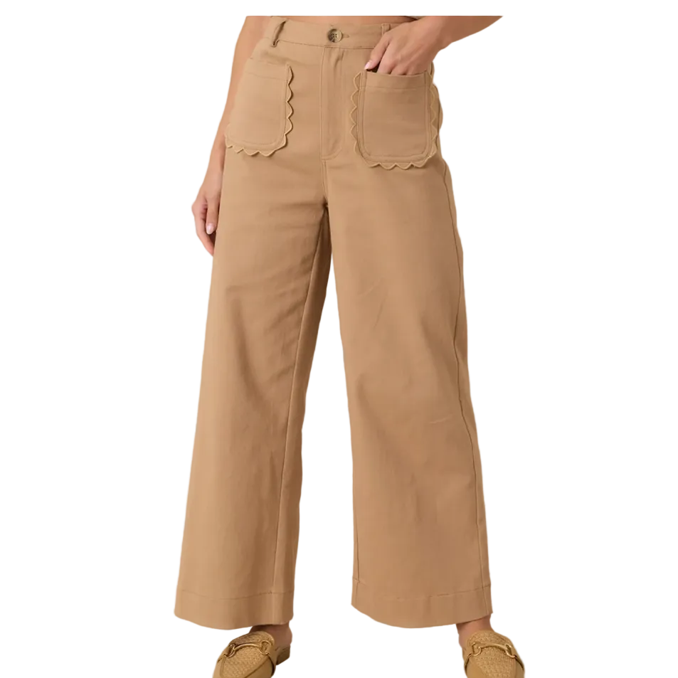 A person wearing tan wide-leg cropped pants with scalloped pocket edges, shown from the waist down against a plain beige studio background.