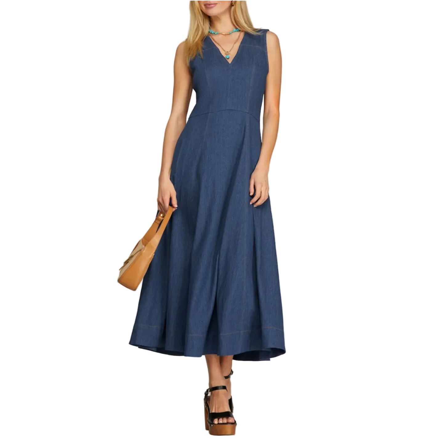 Woman wearing a blue dress holding a brown handbag on a plain background