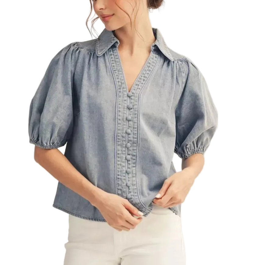 Woman wearing a denim blouse with puff sleeves on a plain background
