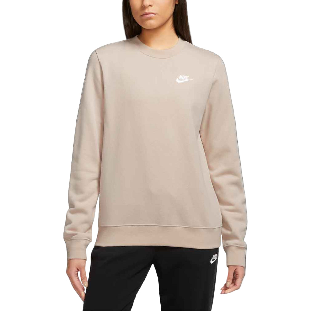 Person wearing a beige Nike sweatshirt and black pants on a white background
