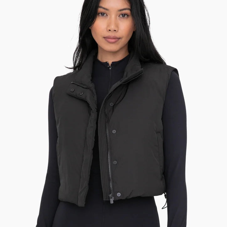 Woman wearing a black vest over a black shirt on a white background